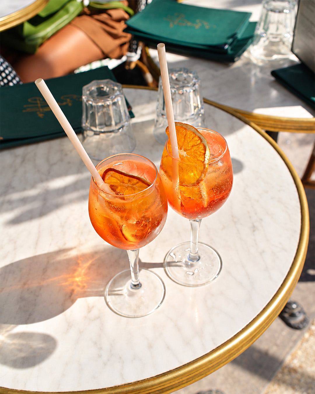 Deux spritz servis sur une table en marbre en terrasse