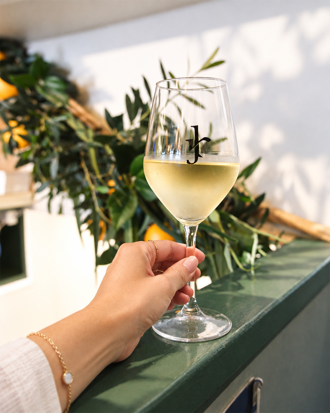 Verre de vin blanc tenu devant la végétation de la trattoria