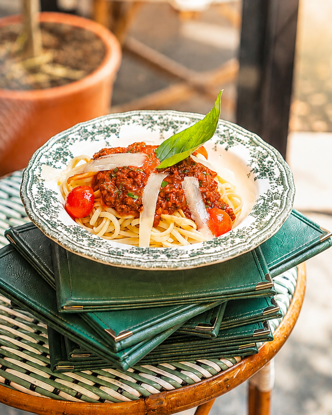 Assiette de pâtes italiennes posée sur plusieurs menus verts La Casa di Alfio